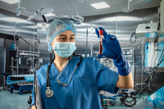 Young female nurse scientist looking on test tube with blood in operating at hospital