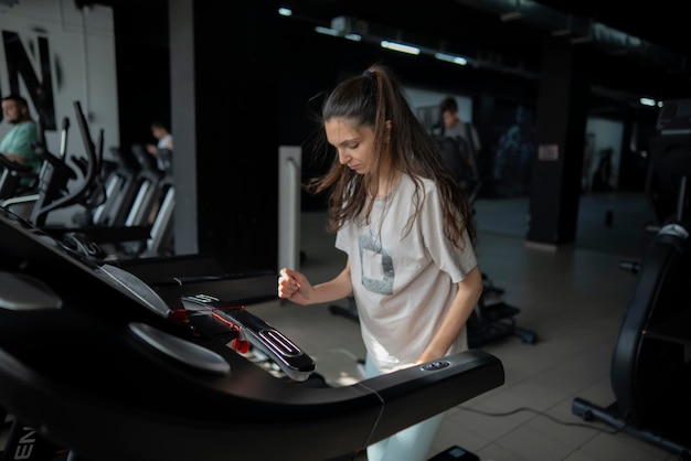 Young female person doing jogging on a treadmill in a fitness center