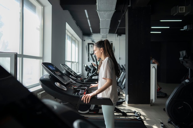 Young female person doing jogging on a treadmill in a fitness center