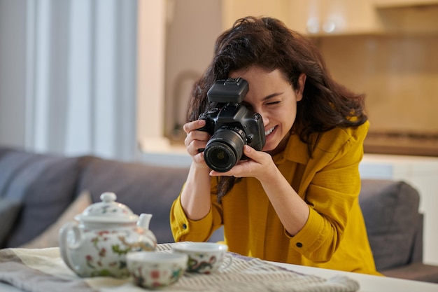 Young female photographer in a mustard shirt with camera in hands