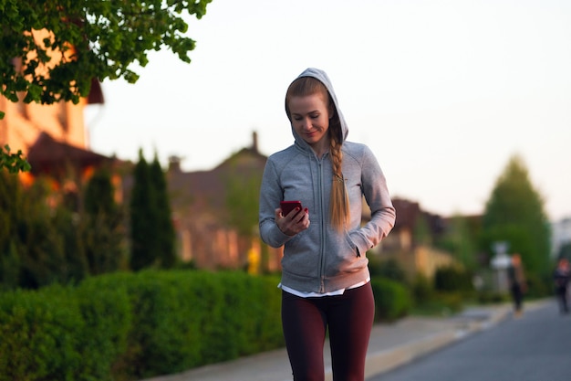 Young female runner, athlete resting after jogging in the city street