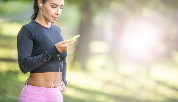 Young female runner listening to motivational music on smartphone app.