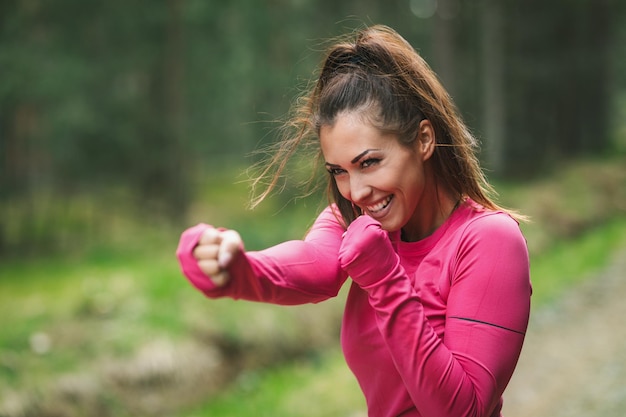 Young female runner warming up before running and having fun at morning in forest.