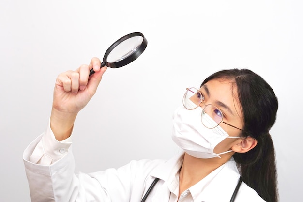 Young female scientist or doctor looking something through a magnifying glass. Research concept.