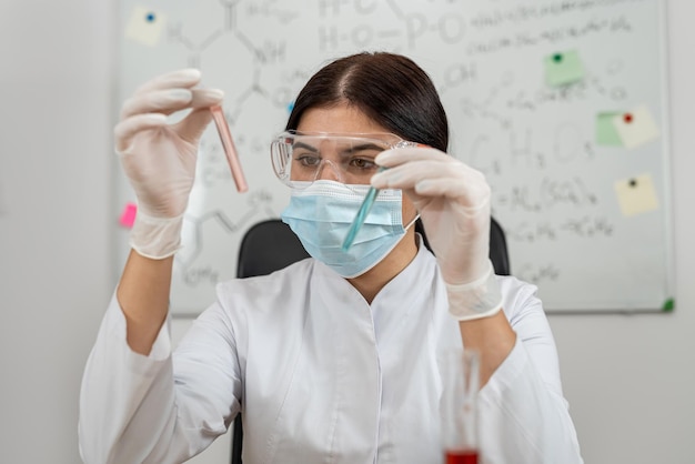 Young female scientist holding test tube flask with color liquid