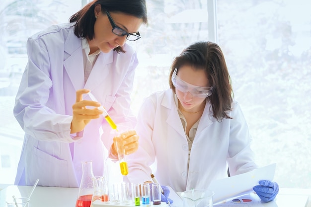 Young female scientist standing with teacher in lab 