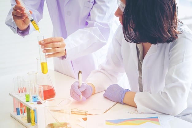 Young female scientist standing with teacher in lab 