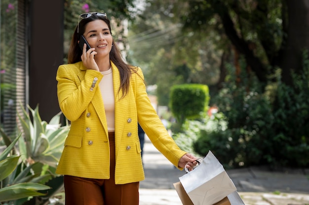 Young female shopping executive carrying her bags while talking on cell phone