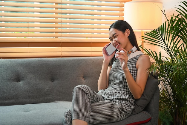 Young female sitting on couch ad talking on mobile phone.