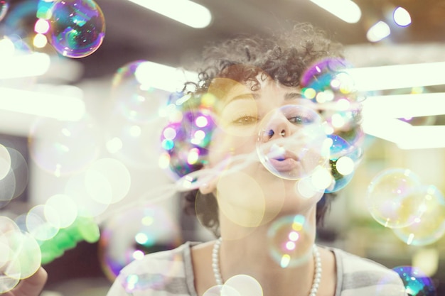 young female software developer having fun while making soap bubbles at modern startup office