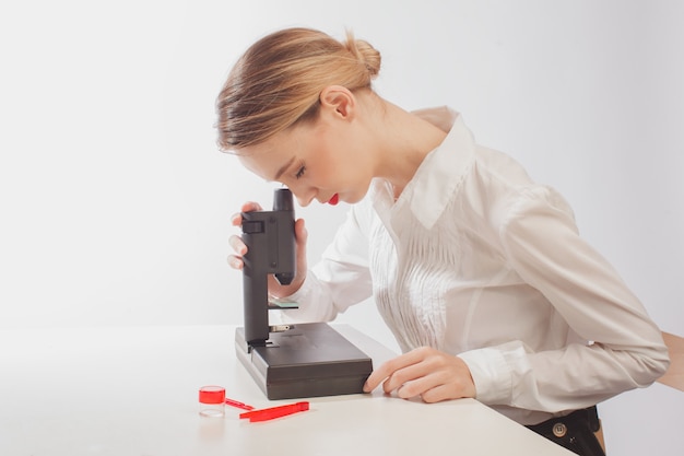 Young female student using microscope in science laboratory