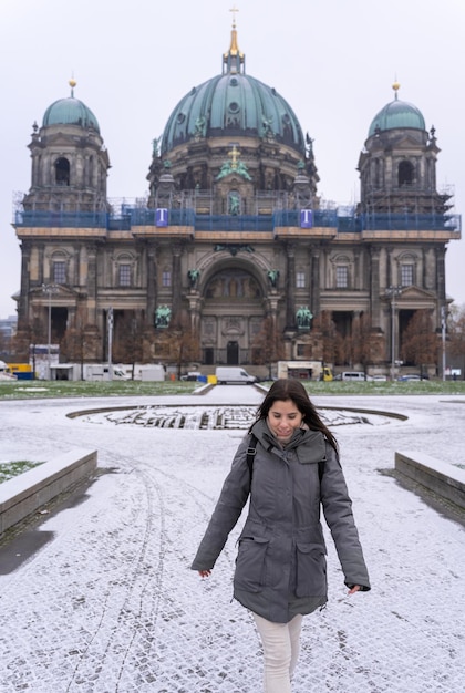 Young female tourist walking in the park in front of the Berlin Cathedral with snow all over the ground