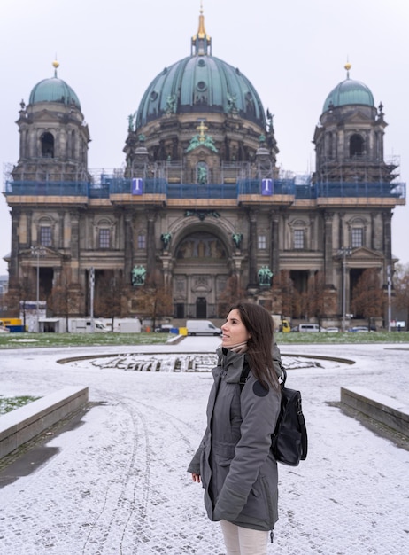 Young female tourist walking in the park in front of the Berlin Cathedral with snow all over the ground