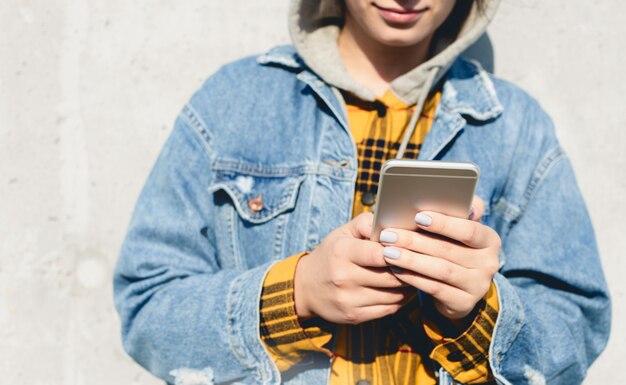 Young female using his smartphone on the street. Woman texting on her phone