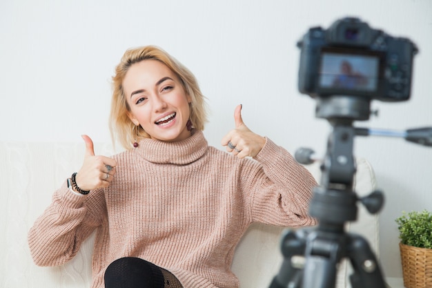 Young female vlogger next to video camera at home