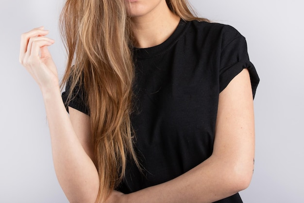 Young female wearing a black short sleeve t-shirt with a white wall in the background