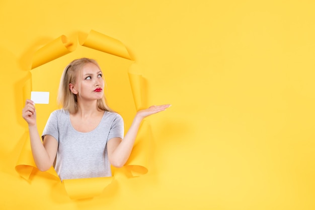 Young female with credit card on a yellow wall