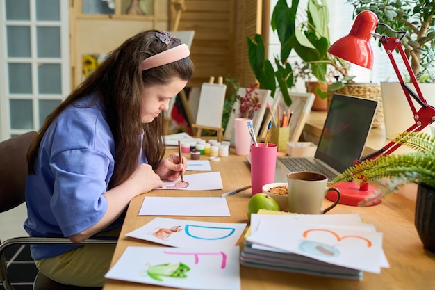 Young female with down syndrome drawing letters with crayons on paper