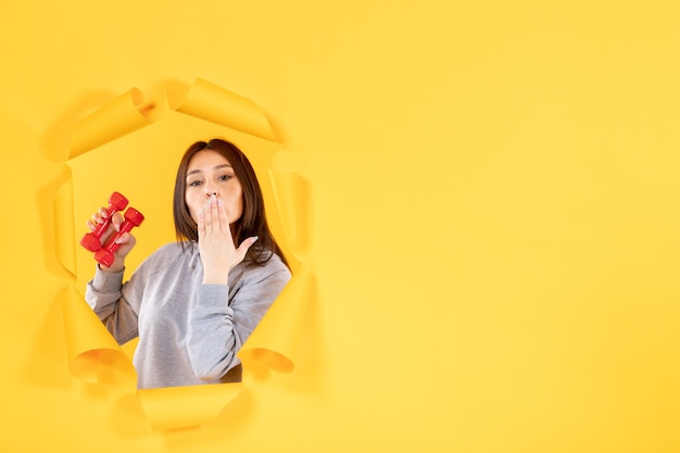 young female with dumbbells on yellow background gym exercise athlete fit