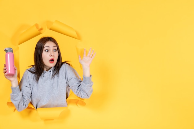 young female with pink bottle on yellow background athlete fit indoor