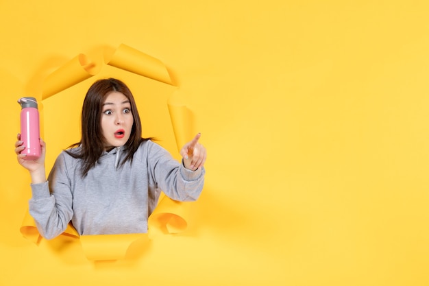 young female with pink bottle on yellow background gym athlete indoor