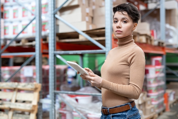 Young female worker of large warehouse using tablet