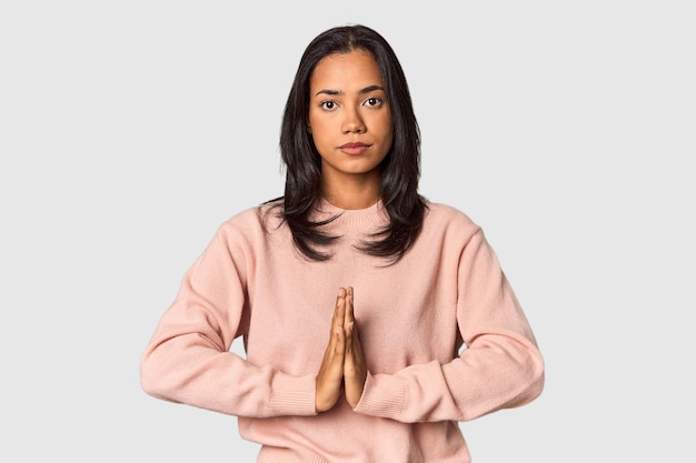 Young Filipina with long black hair in studio praying showing devotion religious person