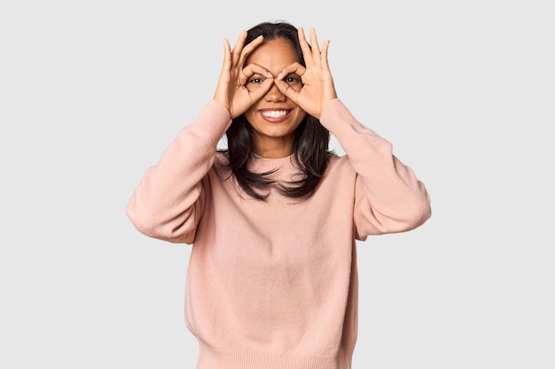 Young Filipina with long black hair in studio showing okay sign over eyes