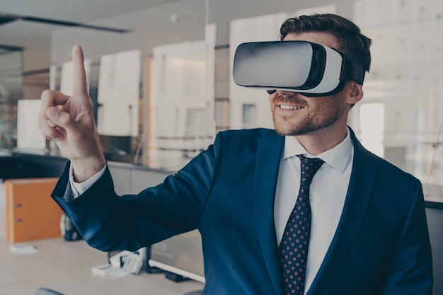 Young financier wearing VR headset glasses, while standing in his office