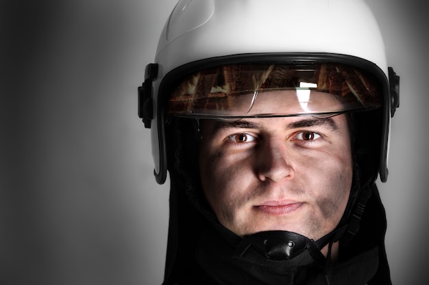 a young firefighter in a white helmet looking against grey background