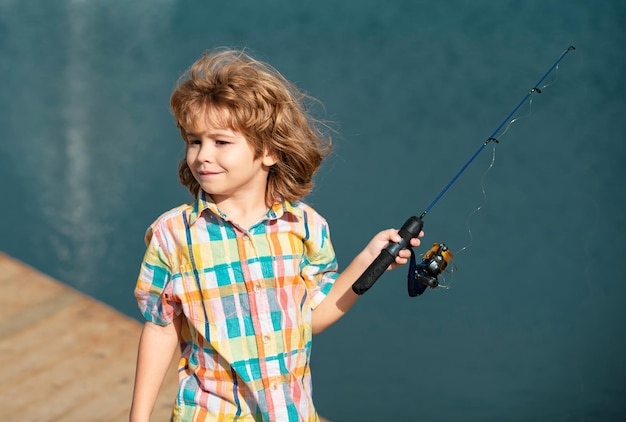 Young fisher child fishing at river bank summer outdoor leisure activity little kid at river bank wi