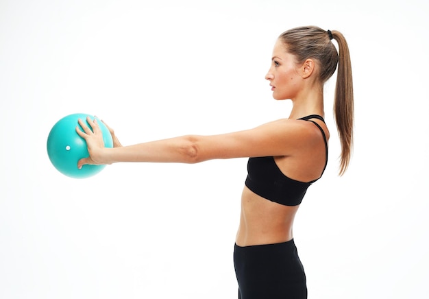 Young fit adult woman doing yoga exercise workout with gymnastics ball