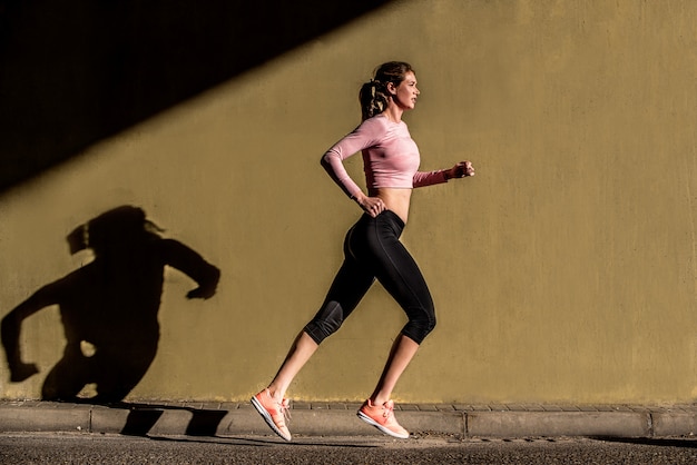 Young fit blonde woman running in the street