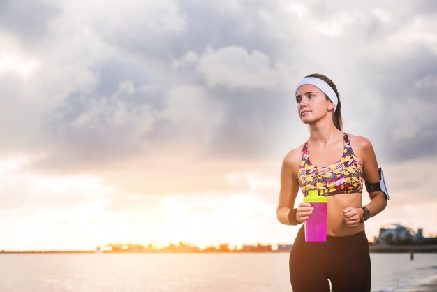 Young fit girl running on beach at sunrise