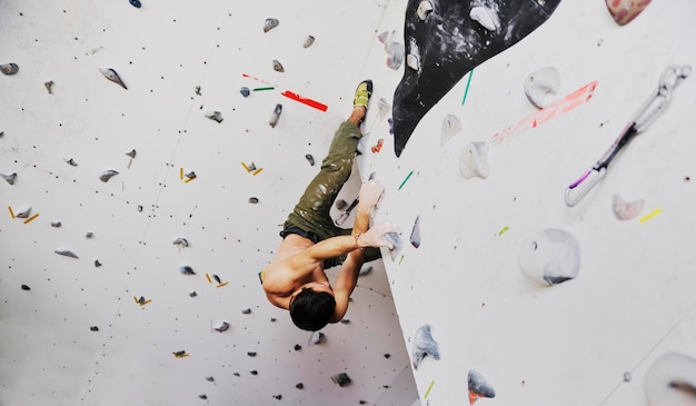 young and fit man exercise free mountain climbing on indoor practice wall