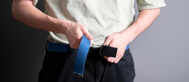 A young fit man tight the pants belt