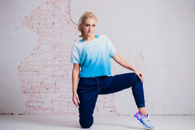 Young, fit and sporty woman standing in front of concrete cement wall