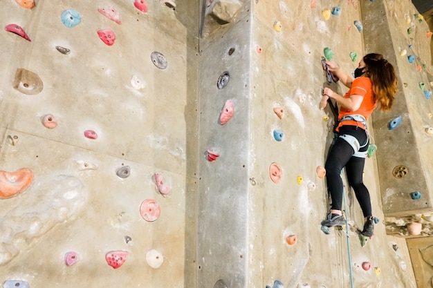 Young fit woman climbing on indoor rock wall.