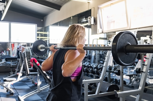 Young fit woman at the gym doing heavylifting exercise. Female athlete at a fitness room working out with barbell