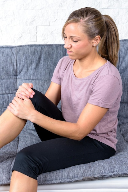 Young fit woman holding her knee; pain contorted face