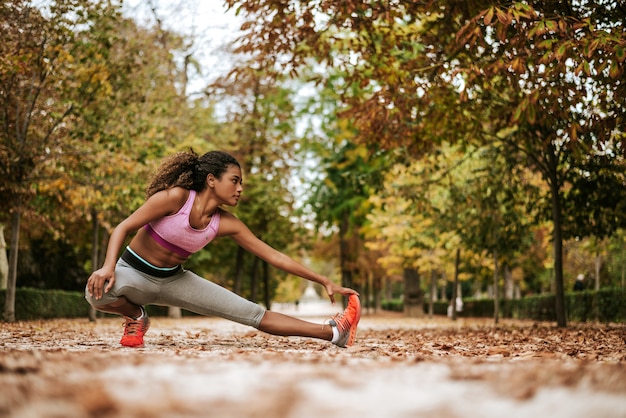 Young fit woman preparing for autumn training in park.