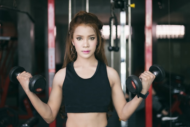 young fitness asian woman exercise with machine Cable Crossover and lifting dumbbells and barbells i