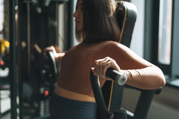 Young fitness brunette woman training for hand muscles equipment at gym selective focus