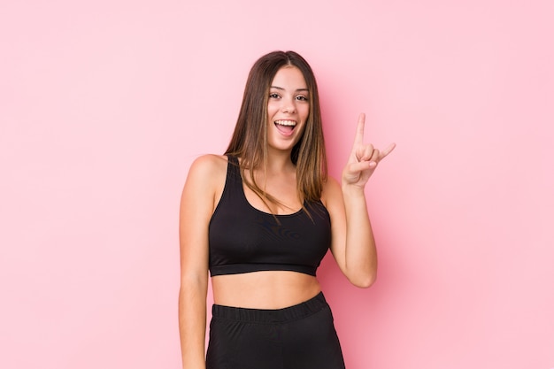 Young fitness caucasian woman showing a horns gesture