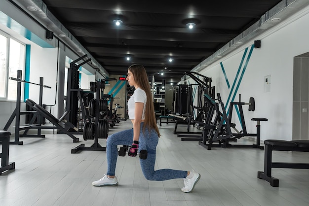 Young fitness female trainer doing exercise and lifting dumbbells weights gym