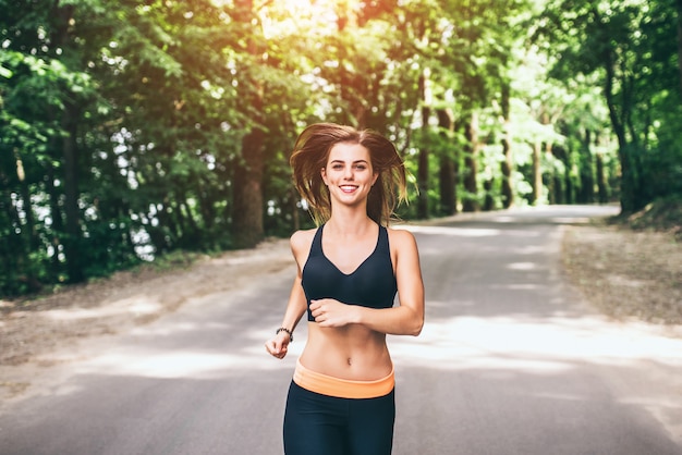 Young fitness girl running and listening music in the park