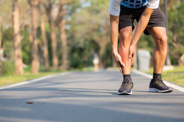 Young fitness man holding his sports leg injury. muscle painful during training