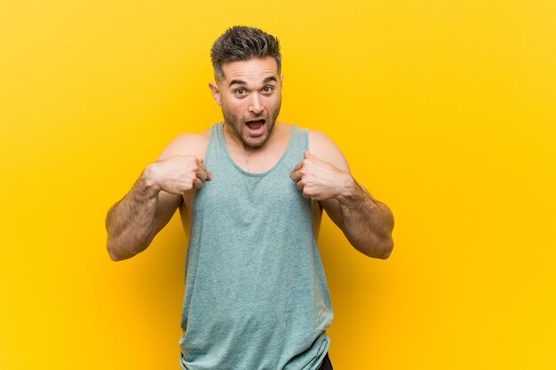 Photo young fitness man  surprised pointing with finger, smiling broadly