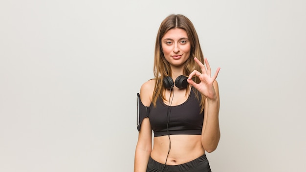 Young fitness russian woman cheerful and confident doing ok gesture