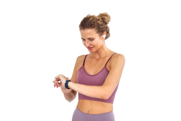 Young fitness woman looking at screen of smart bracelet isolated on white background